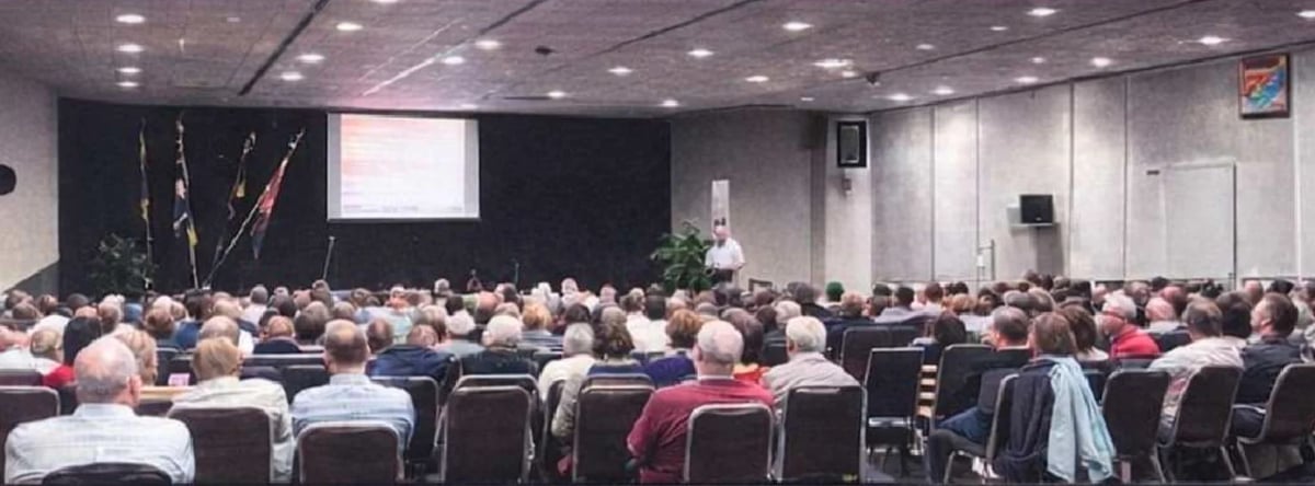 Dr Doyle presenting at a conference with attendees in a large meeting room